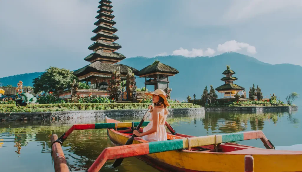 bali vs lombok - woman paddling a boat near a temple in Bali